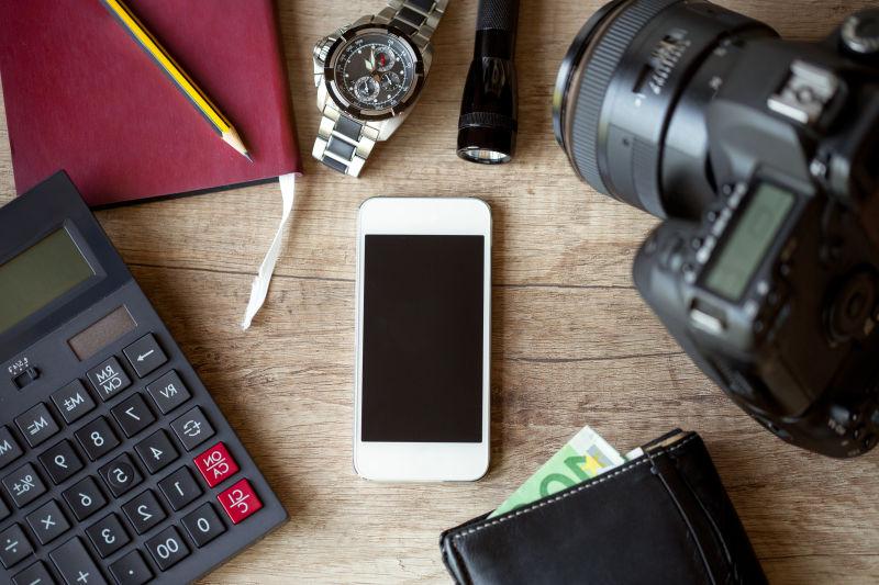 木桌上的手机相机和手表等旅行用的电子产品