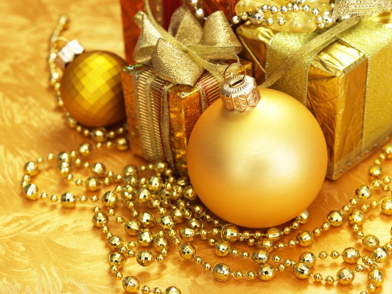 金色背景上的金色的圣诞球和礼物盒子