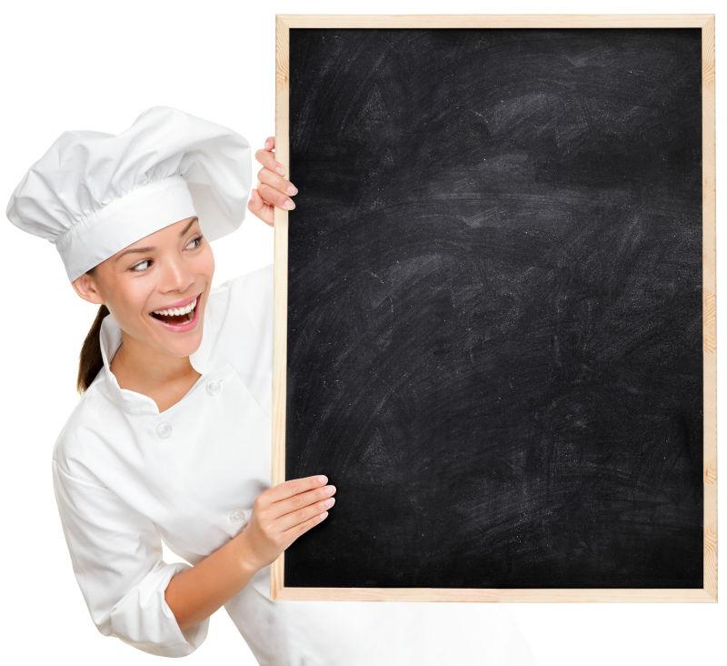穿着厨师制服看起来高兴兴奋的厨师显示空白菜单标志黑板