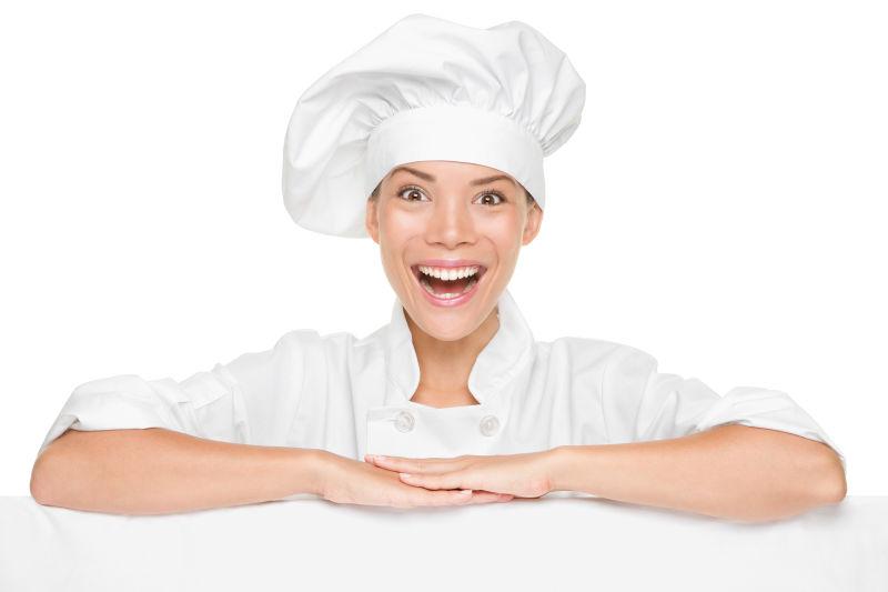 孤立在白色背景的多元文化的亚洲女性厨师兴奋微笑着显示标志广告牌