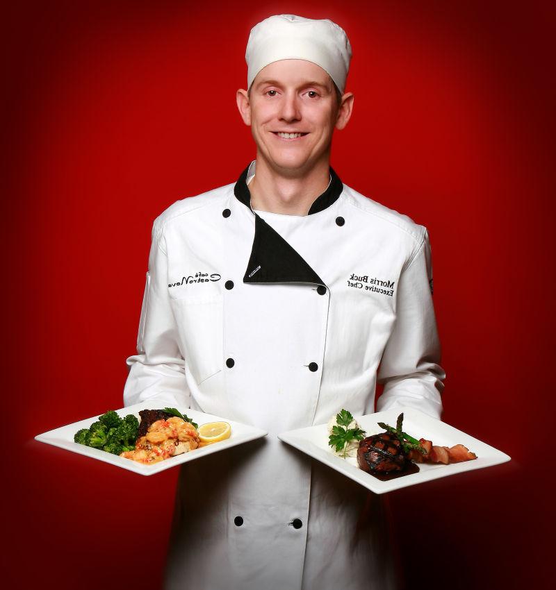 红色背景下端着两个盘子穿着厨师服的厨师
