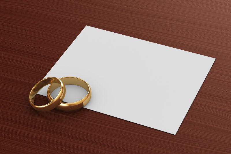 白色方形剪纸上的黄金结婚戒指