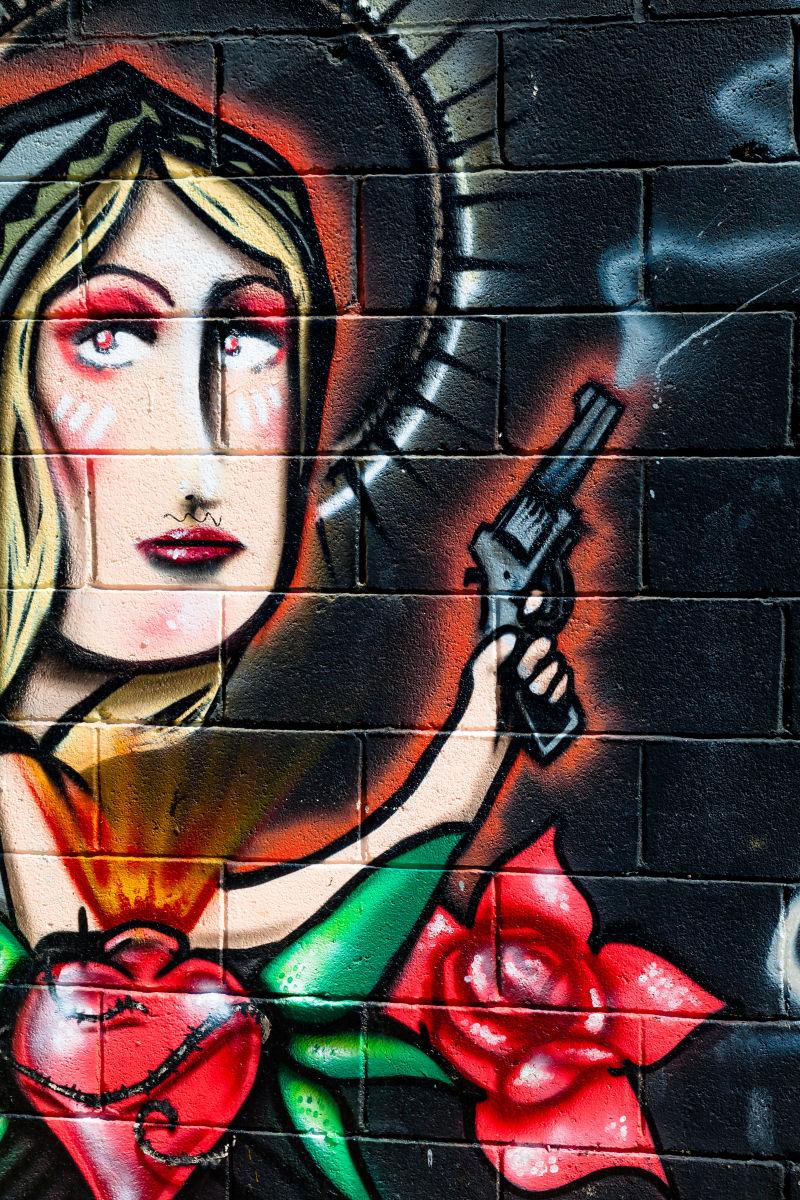 墙壁的拿着枪和玫瑰的女人涂鸦