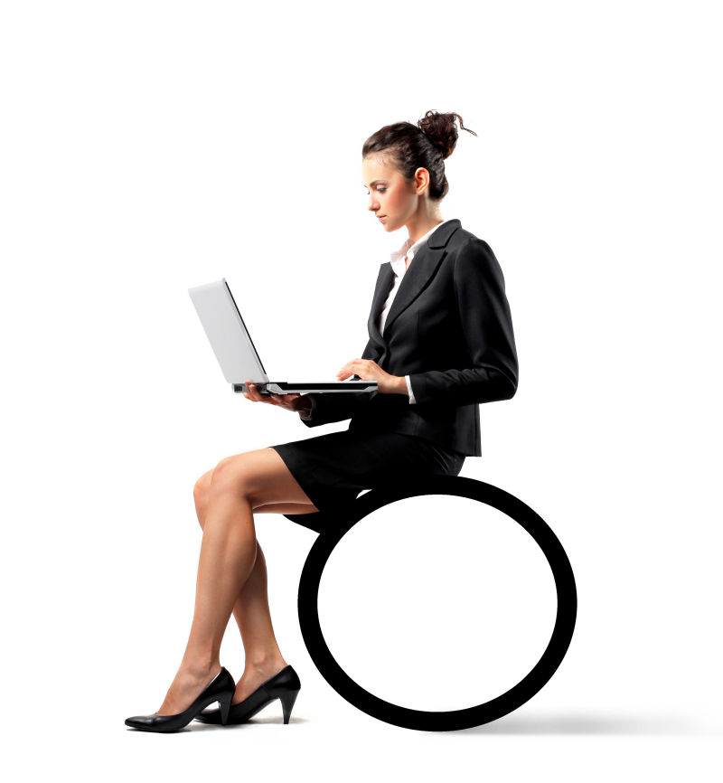 坐在黑色圆球上使用笔记本电脑的女人