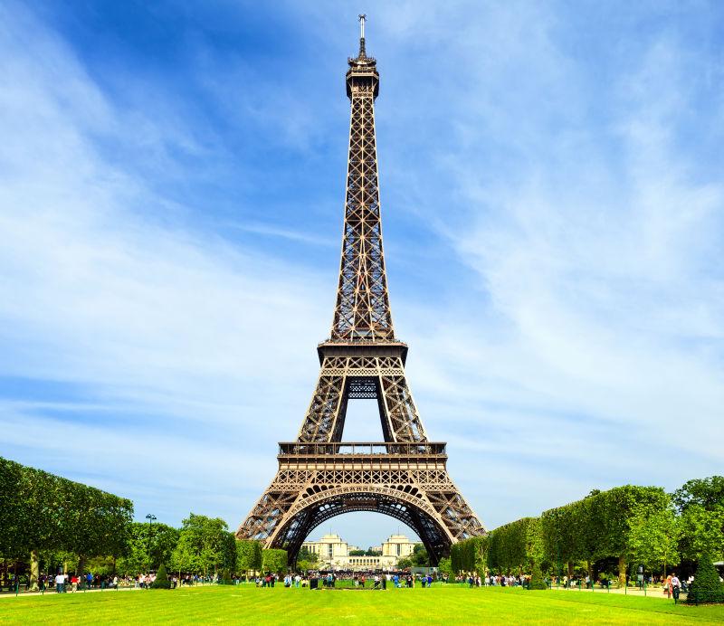 蓝天白云下绿色草地环绕的巴黎埃菲尔铁塔