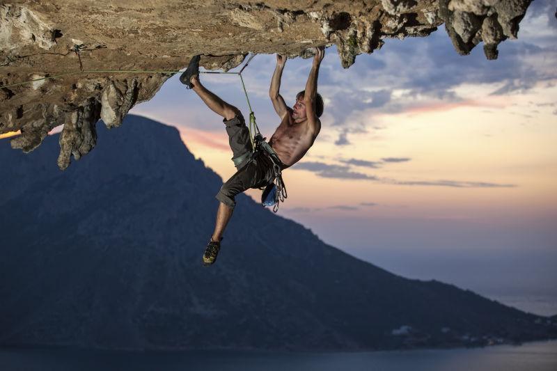 日落时分海岛上的男性攀岩者