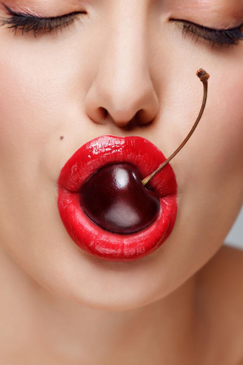 漂亮女人的嘴巴叼着美味樱桃