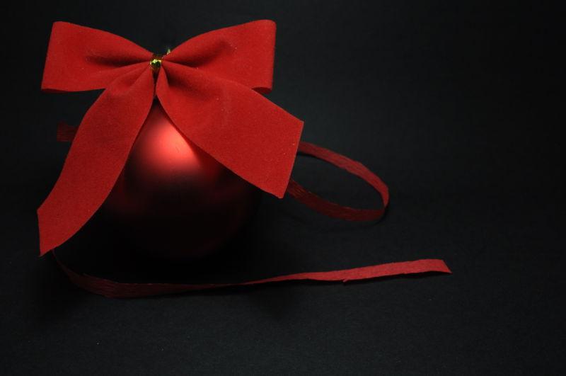 黑色背景下红色的圣诞球和绑成蝴蝶结的丝带