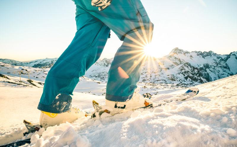 阳光下的群山背景下雪山上滑雪的人