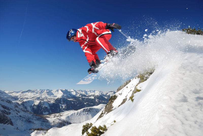 晴天阳光下的群山背景上穿着红色滑雪服滑雪的人