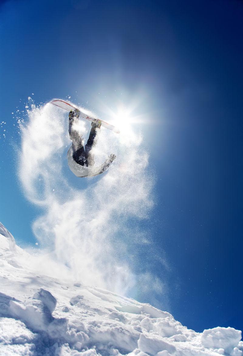 有阳光的蓝天下的跳起来的滑雪人
