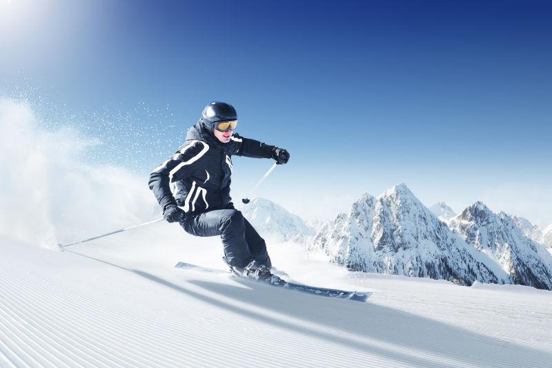 蓝天下雪山上穿着黑色衣服滑雪的人