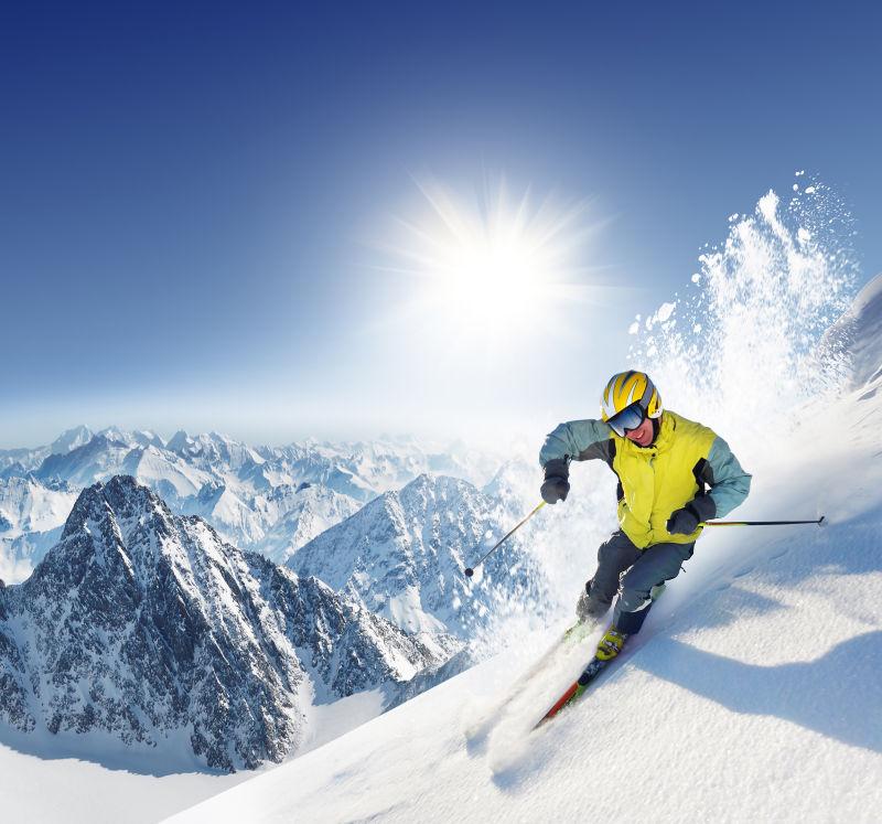 在蓝天和阳光前的雪山上滑雪的人