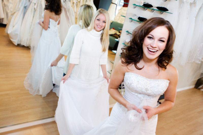 新娘在女售货员的帮助下试穿结婚礼服