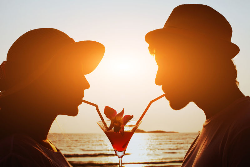 夕阳下在海滩上喝鸡尾酒的情侣
