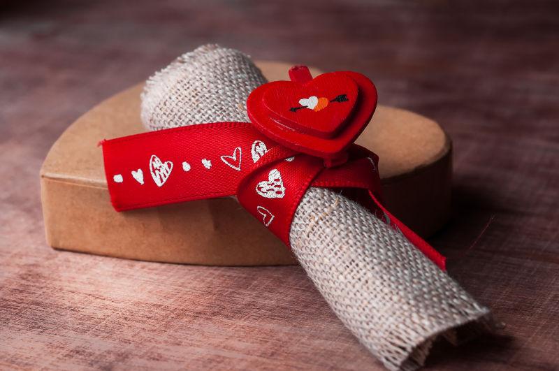 木制背景上红色缎带捆扎的织物和礼物盒