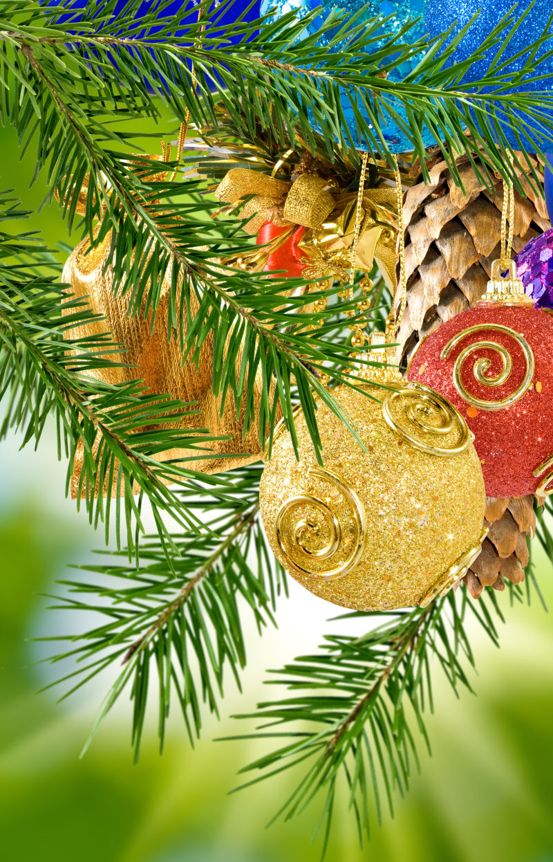 绿色圣诞树背景下的金色和红色的圣诞装饰球