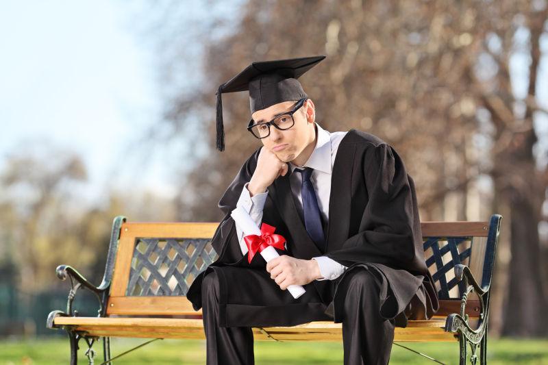 坐在公园的长椅上毕业伤心的大学生