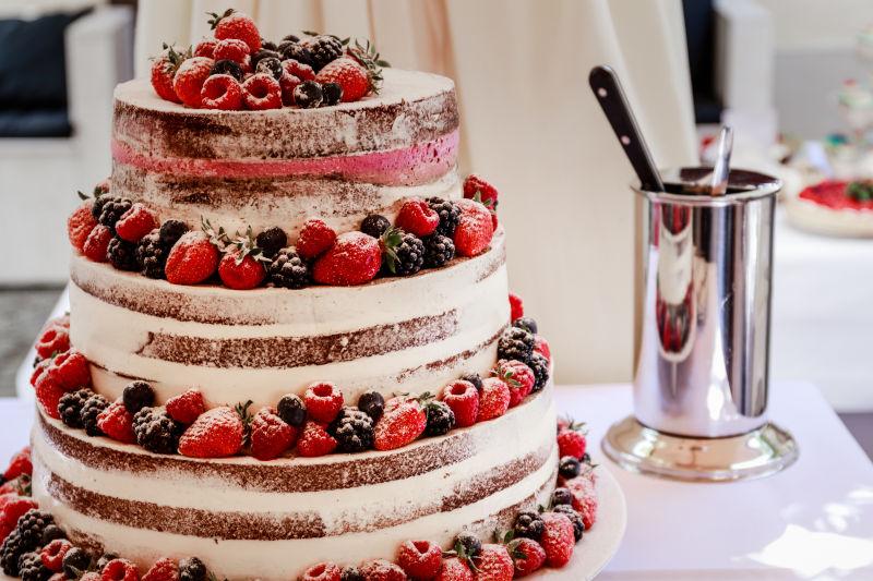 桌上的红色和蓝色的浆果装饰的婚礼蛋糕