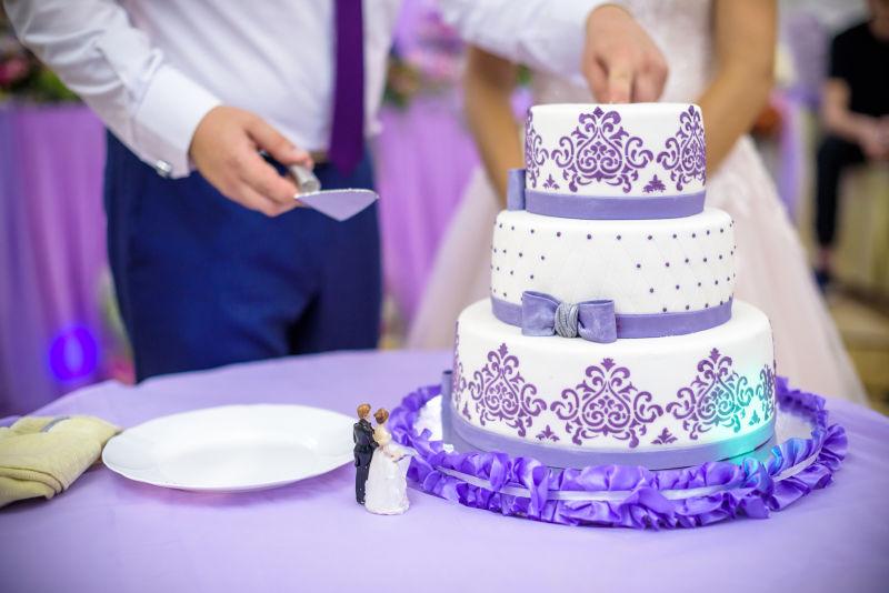 紫色桌上新郎新娘面前的紫色的婚礼蛋糕