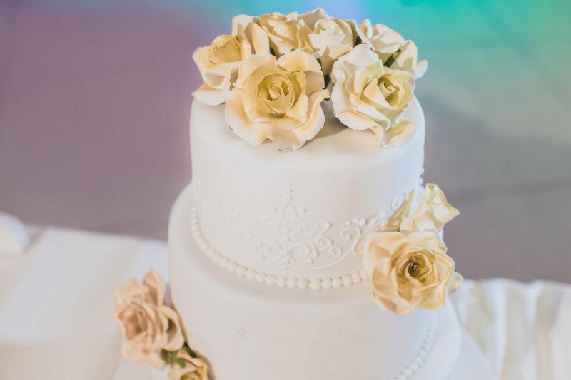 白色桌上的黄色玫瑰花朵装饰的婚礼蛋糕