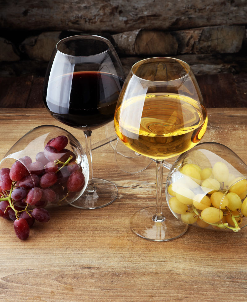 木质板上杯中的红酒和葡萄