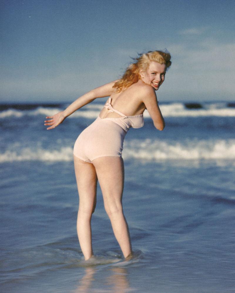 穿着泳衣的性感性感金发女郎在沙滩上冲浪