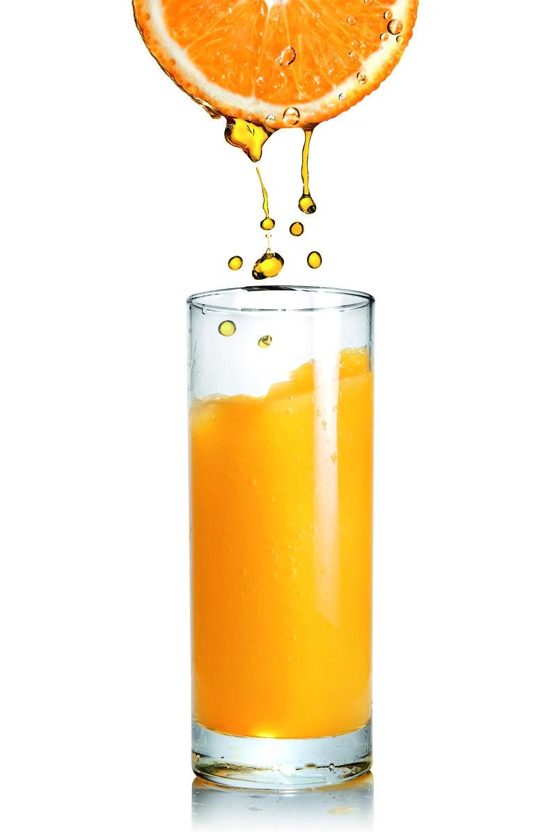 将橙汁倒入白色的玻璃杯中