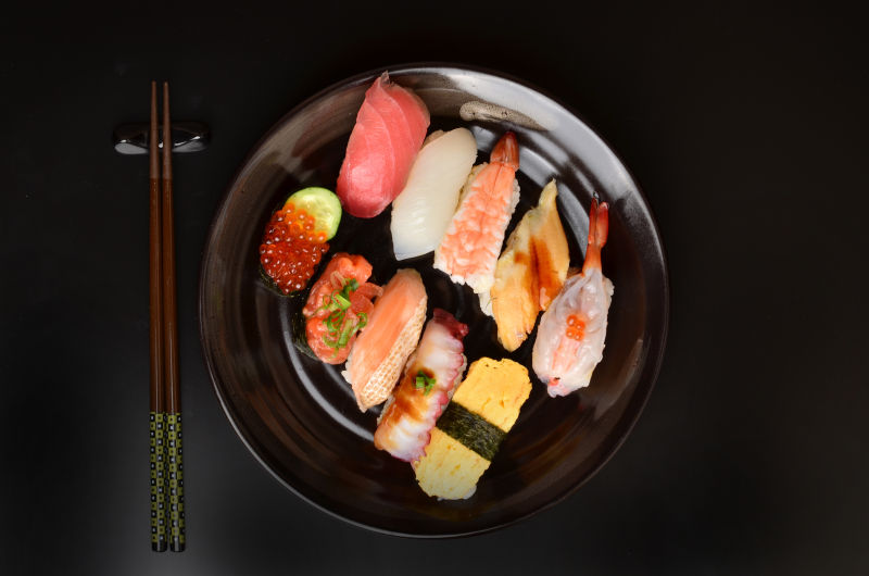 黑色背景中的盘中各种寿司