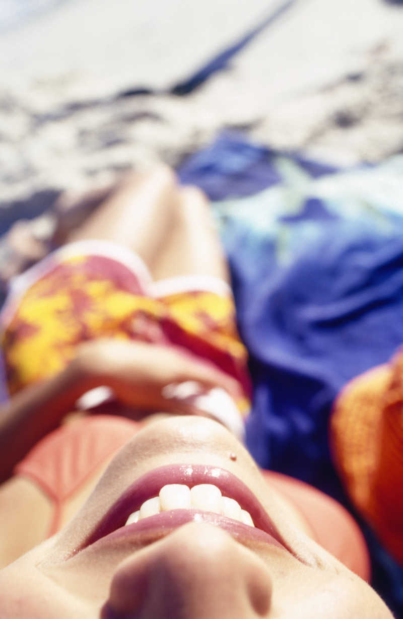 平躺在假日海滩上享受阳光的女子特写