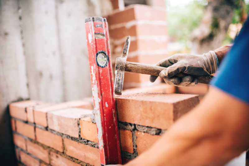 建筑工人用锤子和水平尺砖砌筑水平