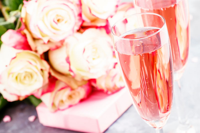 白色和红色玫瑰花束礼品盒粉红色的香槟酒杯为情人情人节灰色背景选择性聚焦