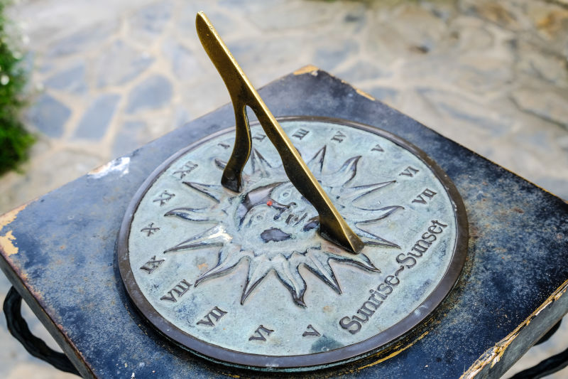 一个铜制日晷的特写镜头安装在花园的石底座上在夏日的阳光下日晷