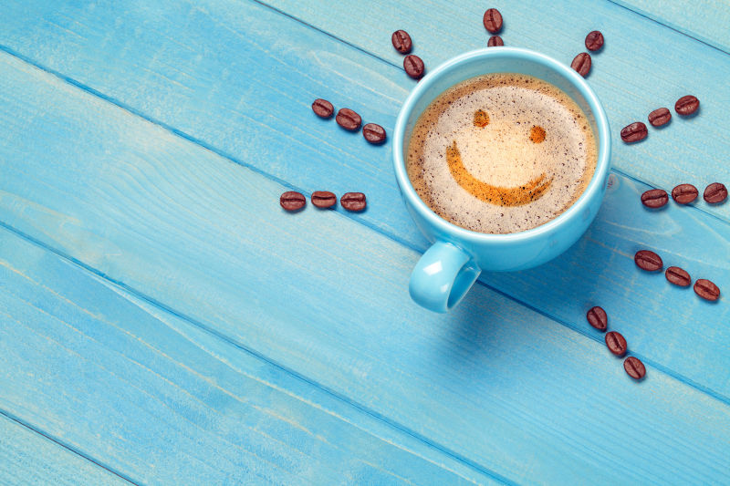 咖啡杯笑脸脸上带着微笑emoji木桌子上的蓝色