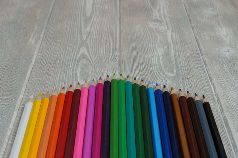 在一张有复印空间的白灰色复古桌上收集彩虹光谱彩色蜡笔