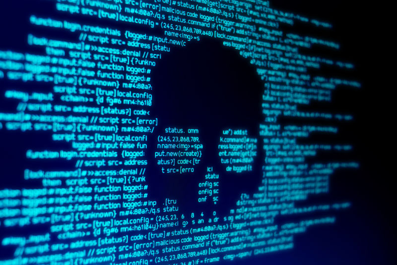 屏幕上的计算机代码头骨代表计算机病毒/恶意软件攻击