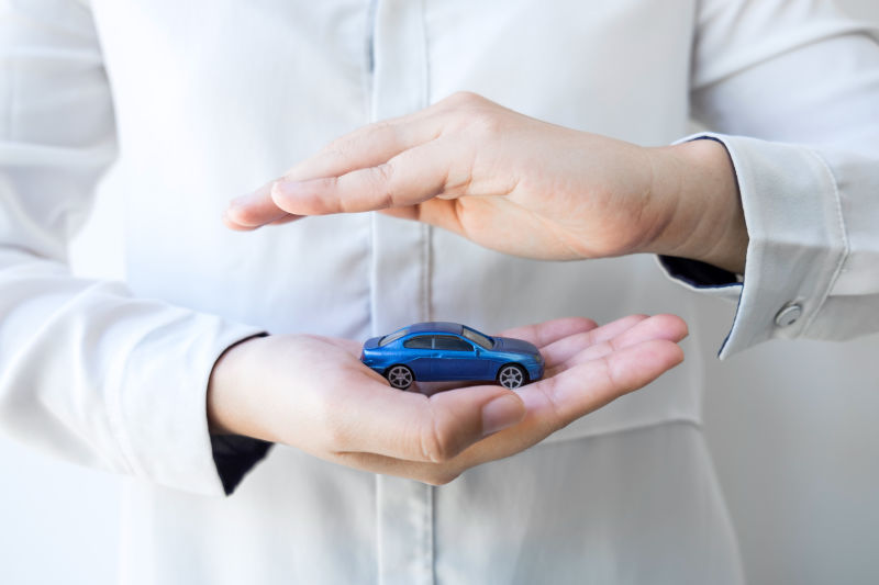 保险和爱护汽车概念-女人用蓝色车保护手势