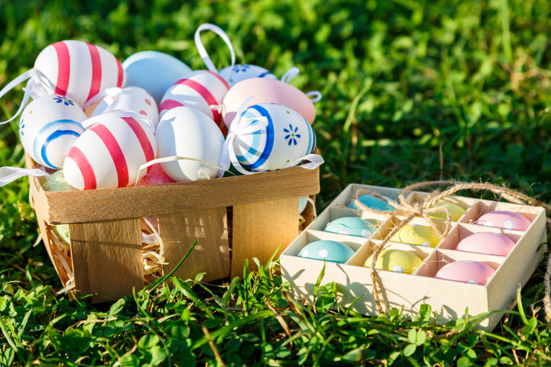 在阳光下-绿色的春草上装饰着盒子里的鸡蛋-复活节快乐！寻找彩蛋-复活节装饰-春天背景