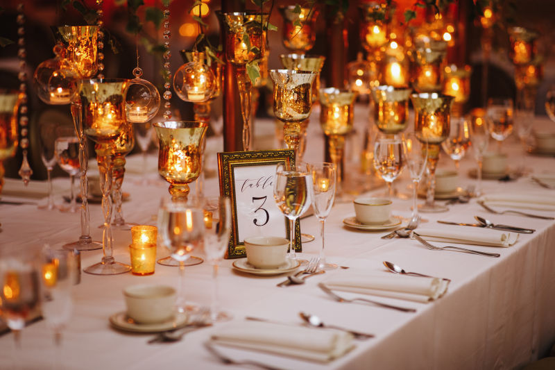 印度婚礼招待晚宴餐厅的桌子上摆放着绿色闪亮的蜡烛和玫瑰金装饰