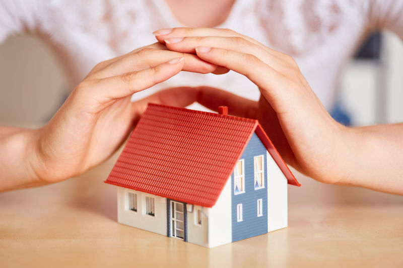 双手保护小房子作为保险概念