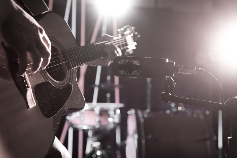 录音室的麦克风录下了一个原声吉他特写镜头彩灯的美丽模糊背景