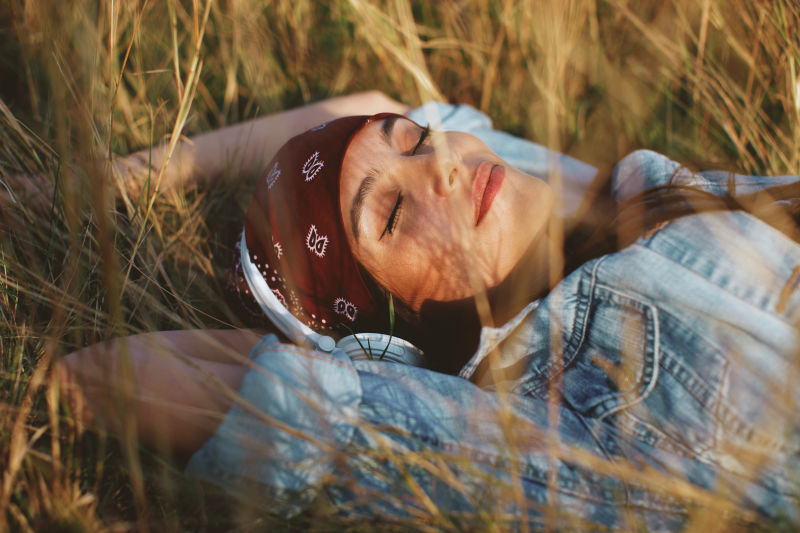 年轻女子的特写镜头听音乐躺在草地上