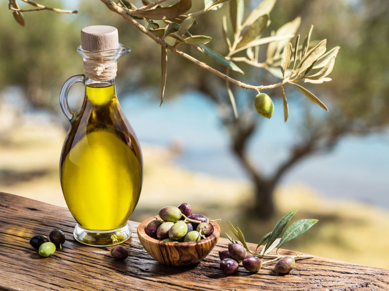 橄榄油和浆果在橄榄树下的木桌上