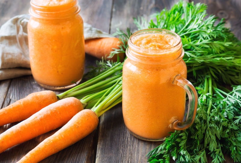 Fresh carrot smoothie在玻璃瓶装在朴素的木质背景上