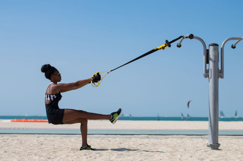 非洲裔年轻女子用特殊绳索进行悬吊训练户外运动活动理念