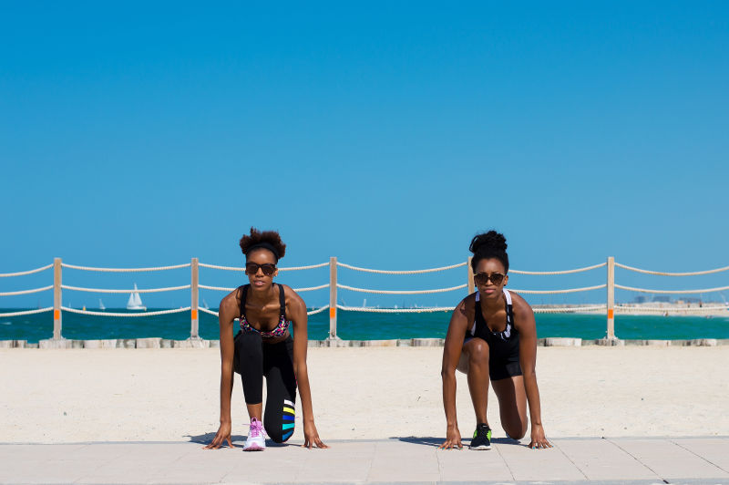 两名穿着运动服和运动发型的非洲女性在阿联酋迪拜的海滩上做运动