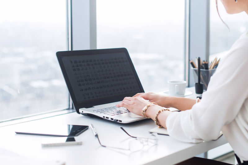 近距离观察一位女性办公室工作人员打字在工作场所处理新项目使用笔记本电脑和Wi-Fi互联网