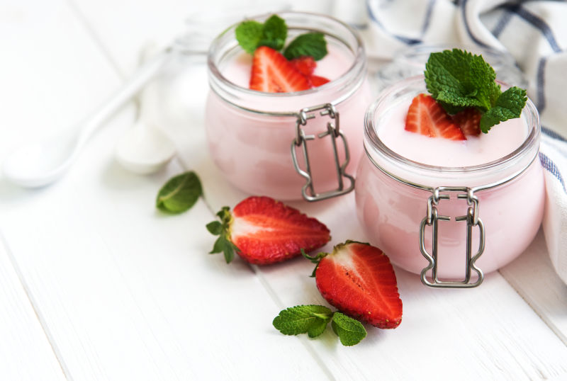 白木桌上的草莓酸奶罐
