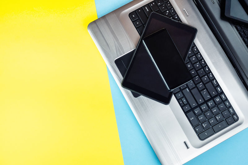 带平板电脑和智能手机的笔记本电脑-背景为蓝黄色