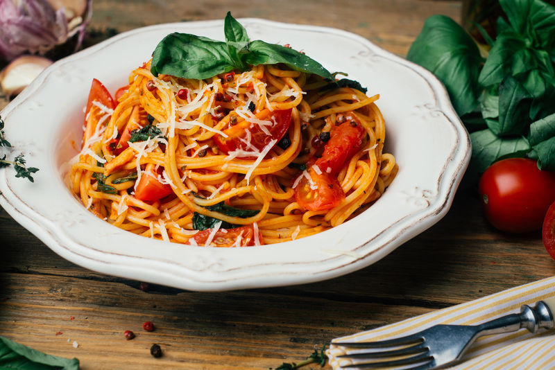 意大利面配番茄酱帕尔马干酪和罗勒在白盘上-经典番茄意大利面：素食番茄罗勒意大利面-旧木背景